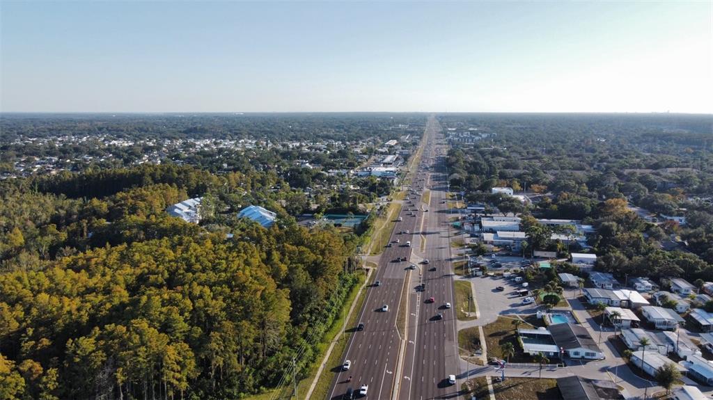 An aerial view shows a multi-lane highway running through a suburban area with surrounding trees — 37542 US HWY 19 N, PALM HARBOR, FL