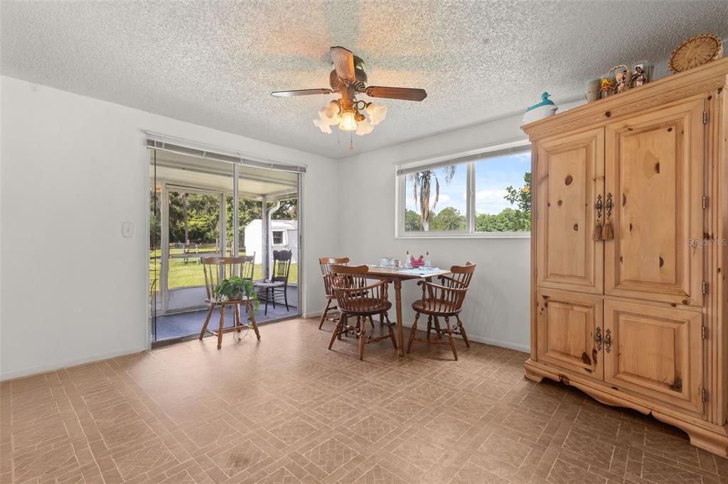 A dining room with tile flooring, a wooden armoire, a ceiling fan, and sliding glass doors — 12631 HOBSON SIMMONS ROAD, LITHIA, FL