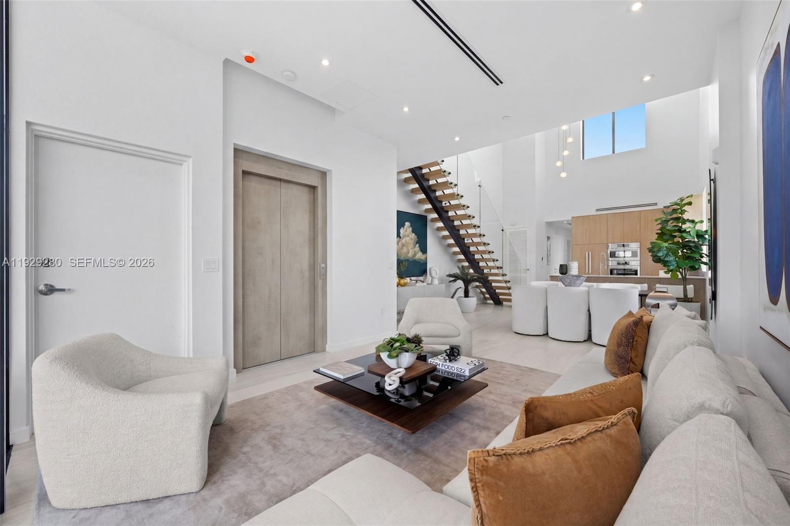 A modern living room features a floating staircase, light wood floors, and neutral furniture — 756 84th St # B, Miami Beach FL 33141, MIAMI BEACH, FL