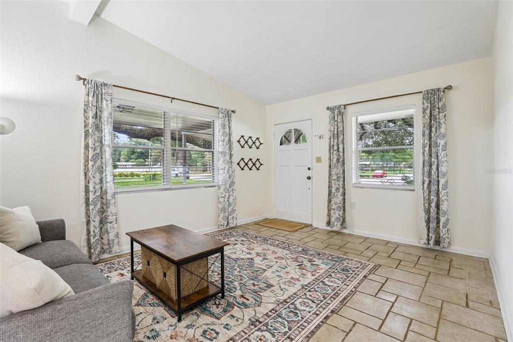A living room features tile flooring, a gray sofa, a coffee table, and two windows — 3707 MARCH AVENUE, ORLANDO, FL