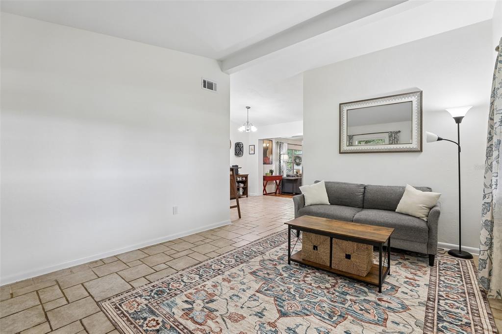 A living room features tile flooring, a gray sofa, a coffee table, and a mirror — 3707 MARCH AVENUE, ORLANDO, FL