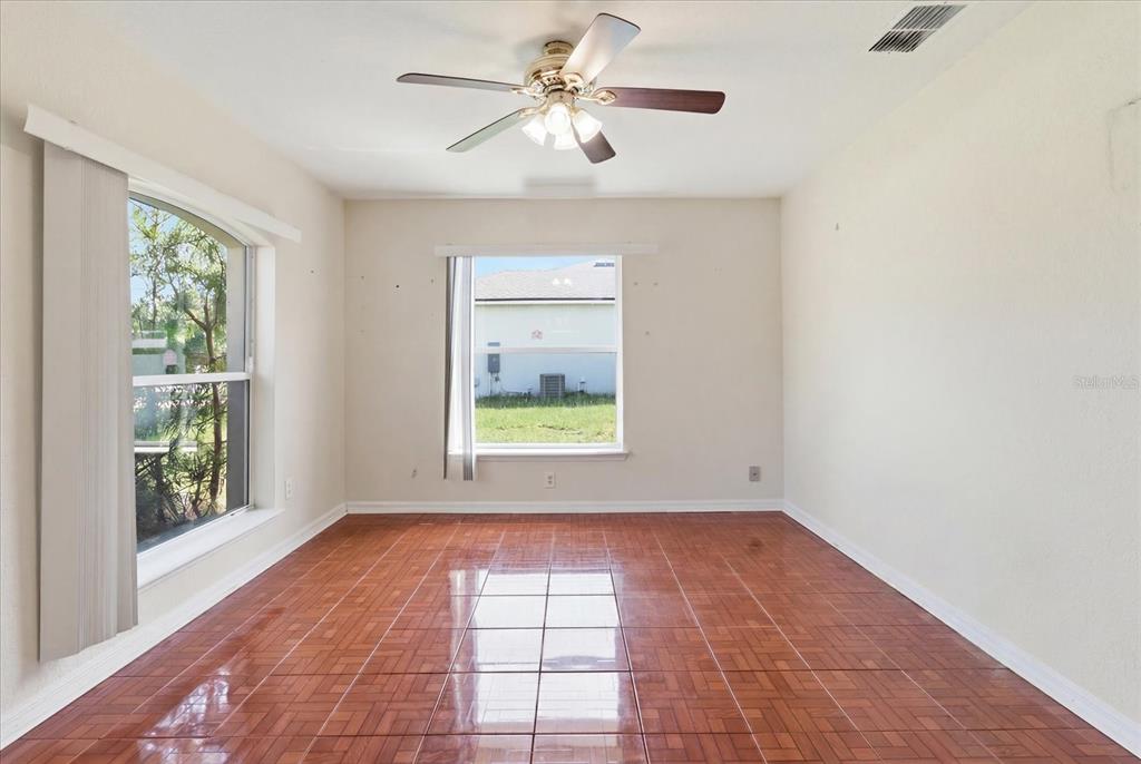 An empty room features glossy brown tile flooring, a ceiling fan, and two windows — 2614 SW 165TH STREET ROAD, OCALA, FL