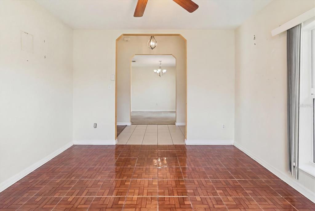 An empty dining room with wood-look tile flooring leads through an archway to another room — 2614 SW 165TH STREET ROAD, OCALA, FL