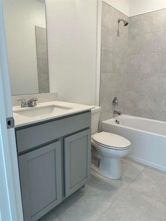 A bathroom features a gray vanity, a white toilet, and a tiled shower-tub combination — 4816 EDENSBRIDGE LANE, KISSIMMEE, FL