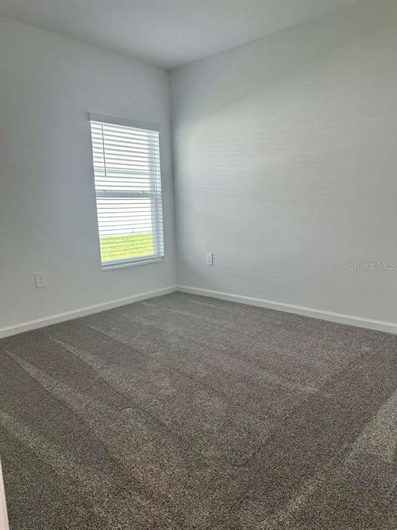 An empty bedroom features gray carpet, white walls, and a single window with blinds — 4816 EDENSBRIDGE LANE, KISSIMMEE, FL