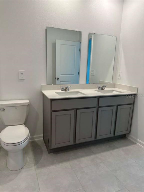A bathroom features a gray double-sink vanity with a white countertop and two wall mirrors — 4816 EDENSBRIDGE LANE, KISSIMMEE, FL