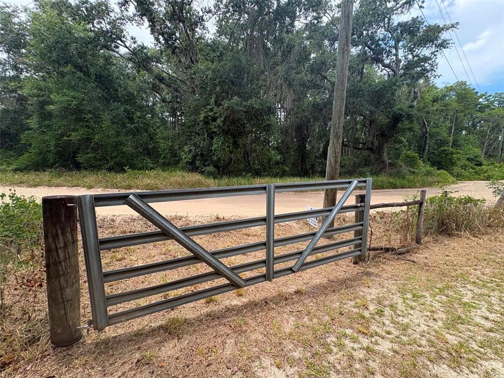 A metal gate is attached to a wooden post at the entrance of a dirt road — 0 MILLSTREAM DRIVE, GROVELAND, FL