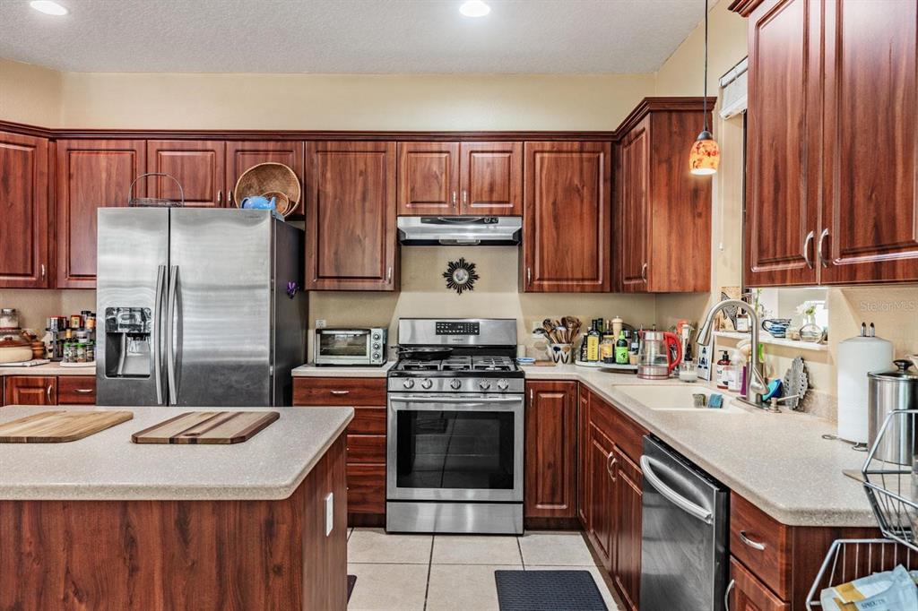 A kitchen with wood cabinets, stainless steel appliances, and light-colored countertops — 10426 MOUNT DORA STREET, NEW PORT RICHEY, FL