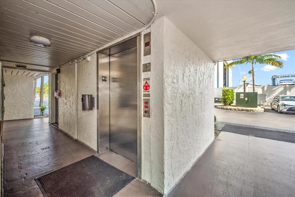 An outdoor elevator entrance is located under a covered walkway near a parking area — 1027 ANGLERS COVE UNIT B502, MARCO ISLAND, FL