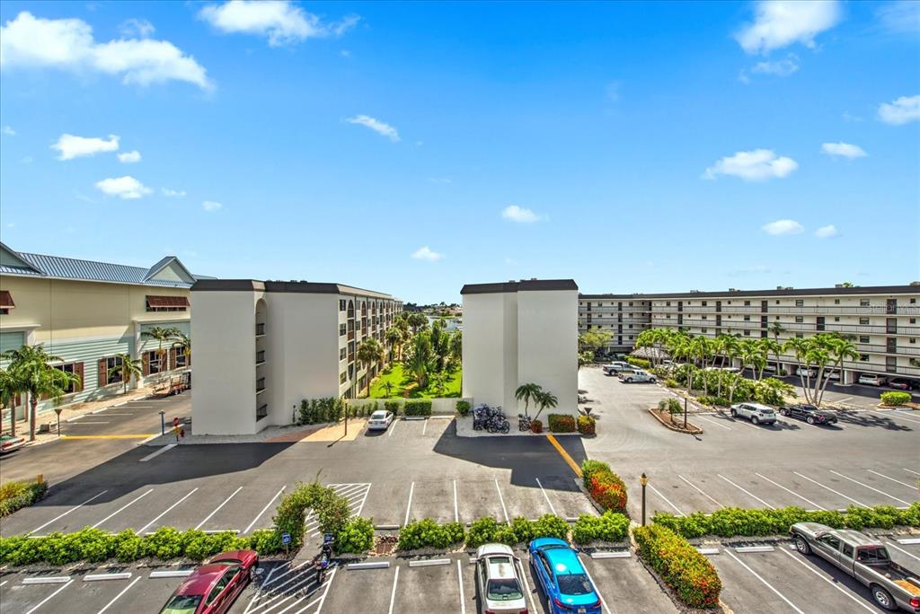 An elevated view shows two multi-story apartment buildings separated by a parking lot and landscaping — 1027 ANGLERS COVE UNIT B502, MARCO ISLAND, FL