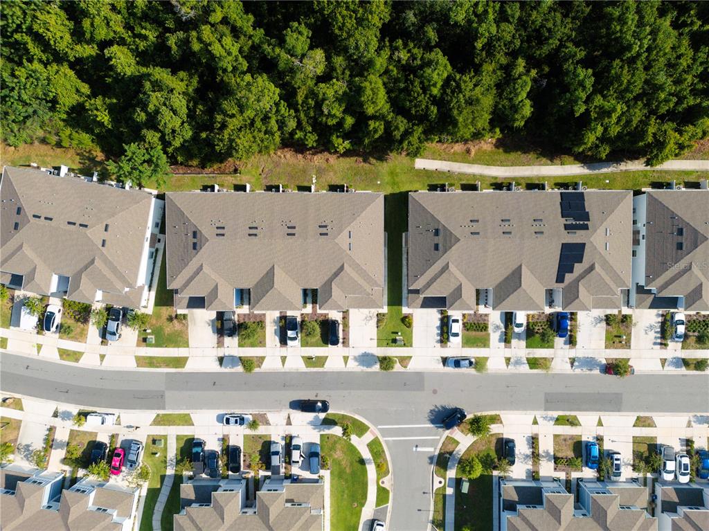 An aerial view shows several townhome buildings with driveways and a surrounding wooded area — 4609 SPARKLING SHELL AVENUE, KISSIMMEE, FL