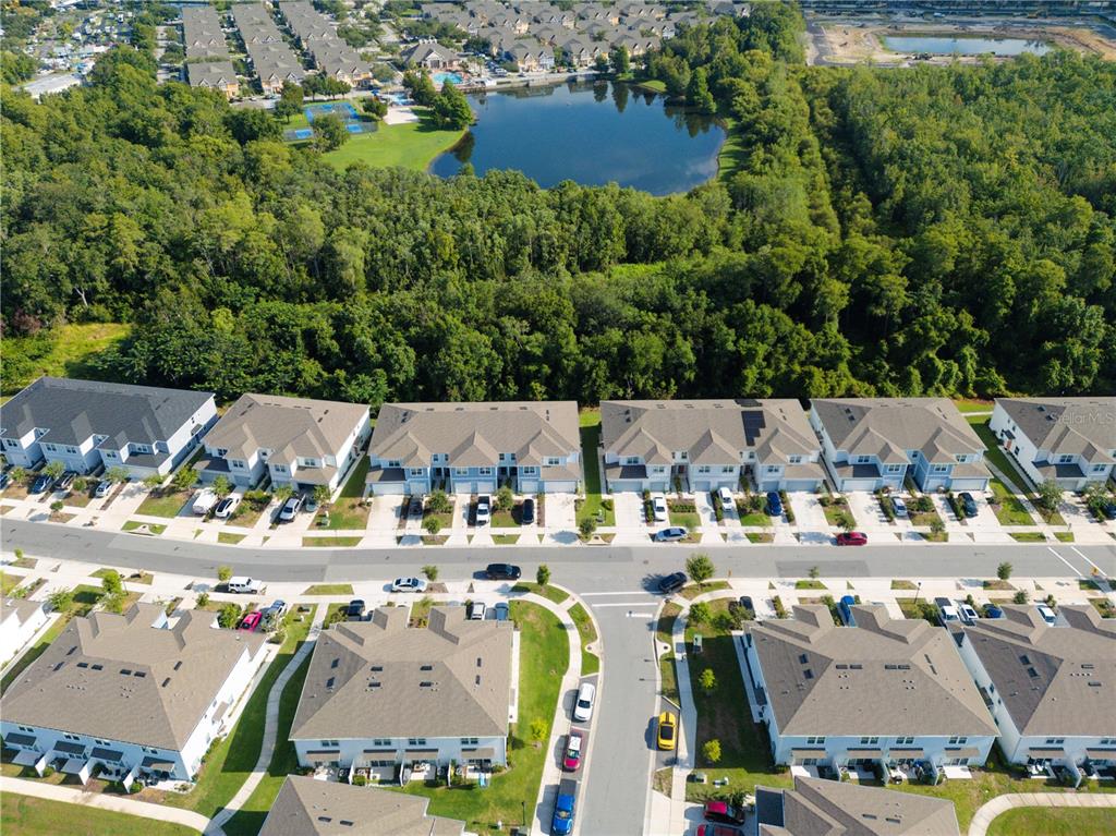 An aerial view shows multiple townhome buildings, a paved street, and a nearby pond — 4609 SPARKLING SHELL AVENUE, KISSIMMEE, FL