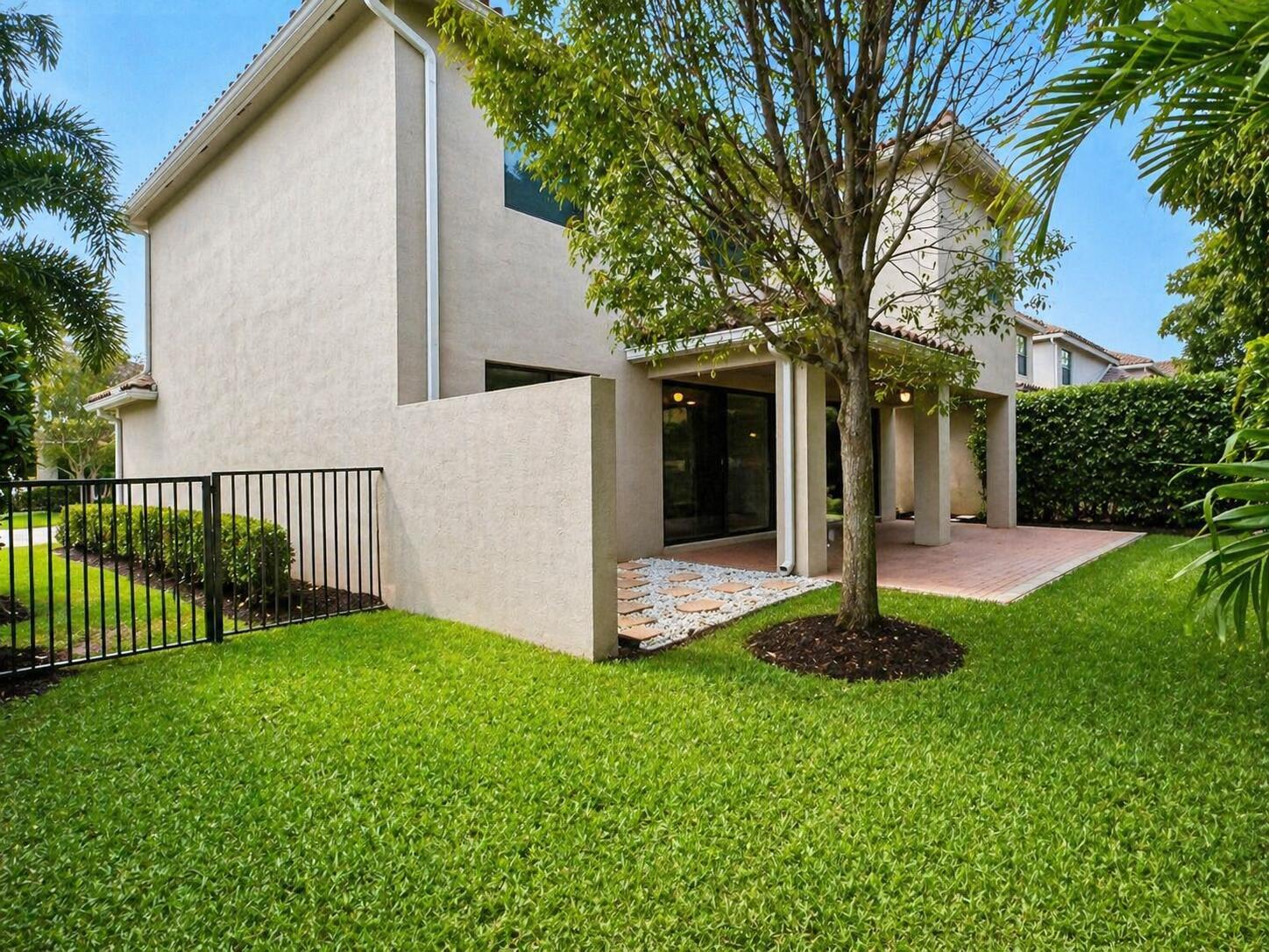 A backyard view featuring a paved patio, a privacy wall, and a large tree — 8079 Snowflake Obsidian Trail, Delray Beach FL 33446, DELRAY BEACH, FL