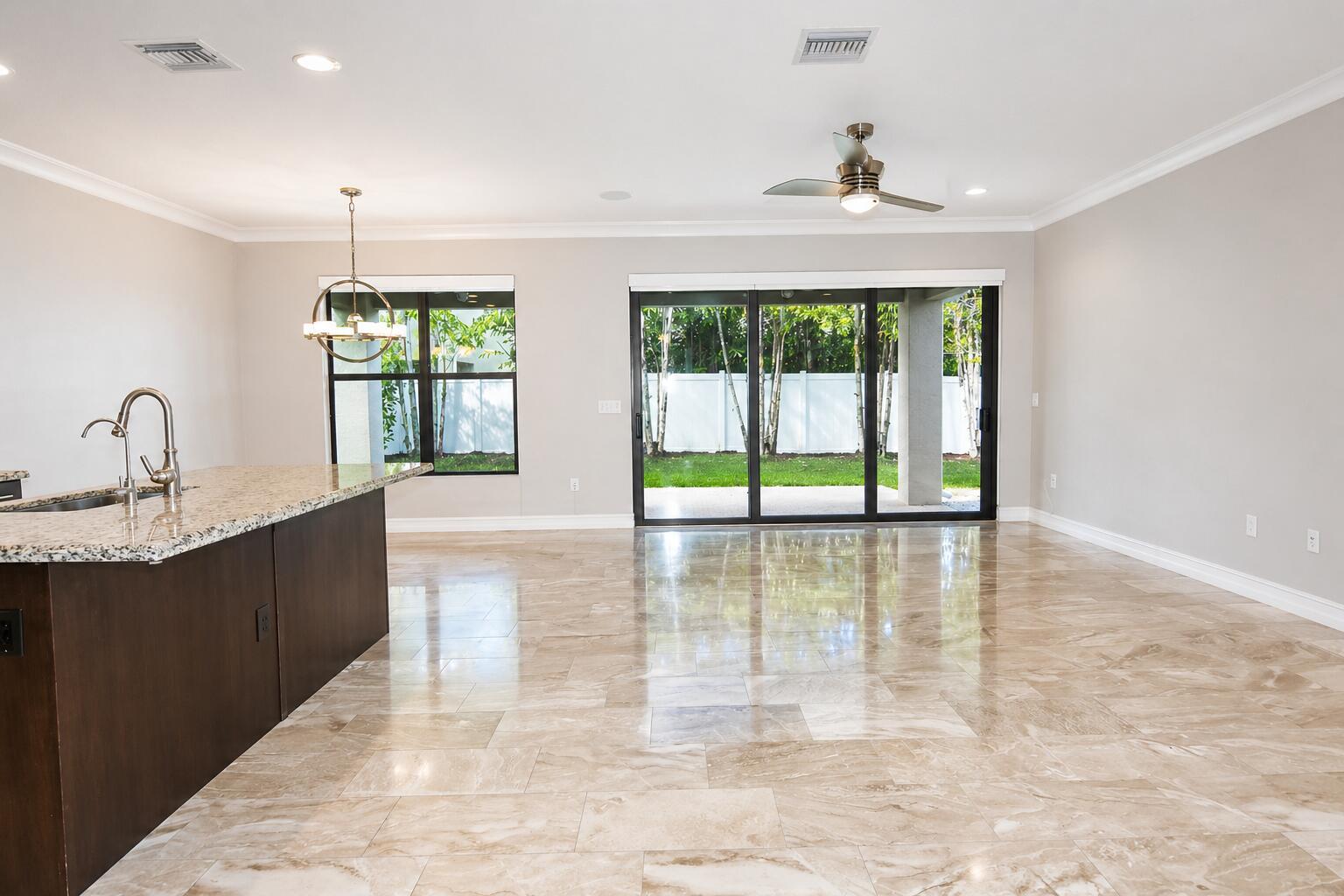 An open-concept kitchen and living area features tile flooring, a granite island, and sliding doors — 8079 Snowflake Obsidian Trail, Delray Beach FL 33446, DELRAY BEACH, FL