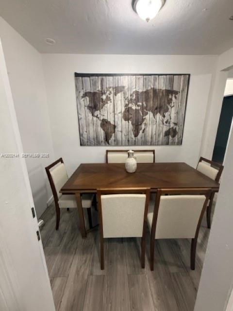 A dining room features a wooden table, four upholstered chairs, and a large world map wall-art — 1419 NW 44th St, Miami FL 33142, MIAMI, FL