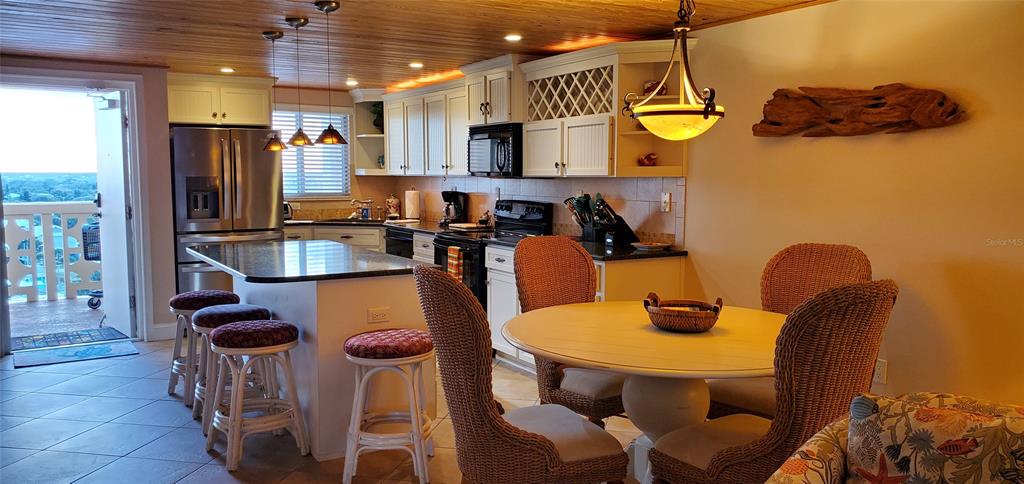 A kitchen with a breakfast bar and dining area features wicker chairs and wood ceilings — 601 N ATLANTIC AVENUE UNIT 8070, NEW SMYRNA BEACH, FL