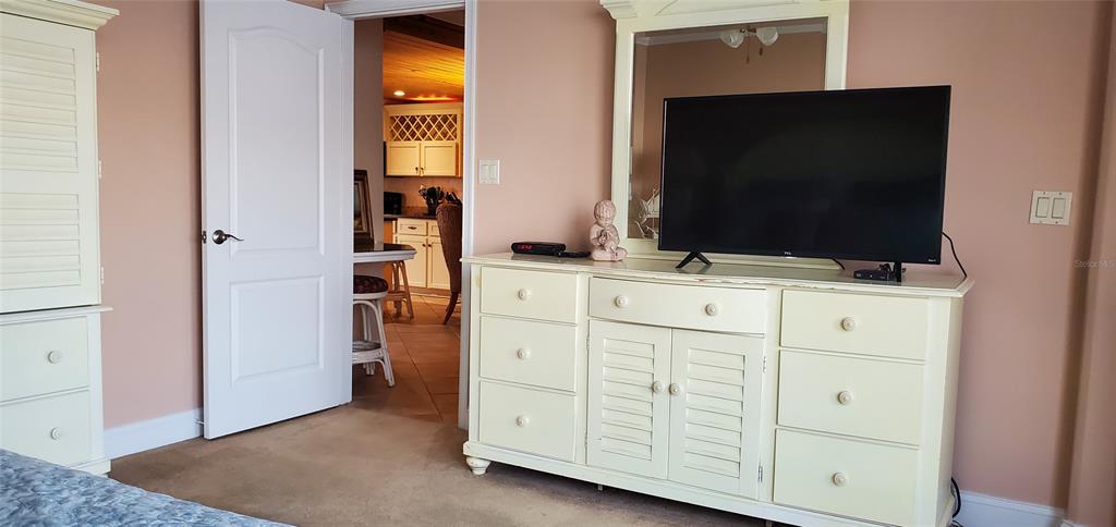 A bedroom features a white dresser with a television and a doorway leading to a kitchen — 601 N ATLANTIC AVENUE UNIT 8070, NEW SMYRNA BEACH, FL