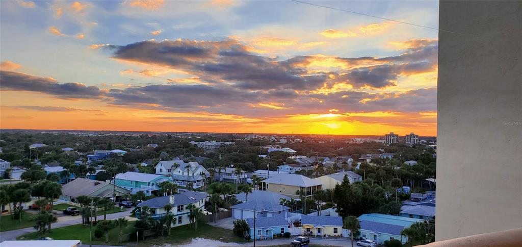 An elevated view of a coastal neighborhood at sunset under a cloudy sky — 601 N ATLANTIC AVENUE UNIT 8070, NEW SMYRNA BEACH, FL