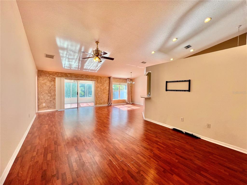A living room with hardwood floors, a ceiling fan, and sliding glass doors to a patio — 30728 IVERSON DRIVE, WESLEY CHAPEL, FL