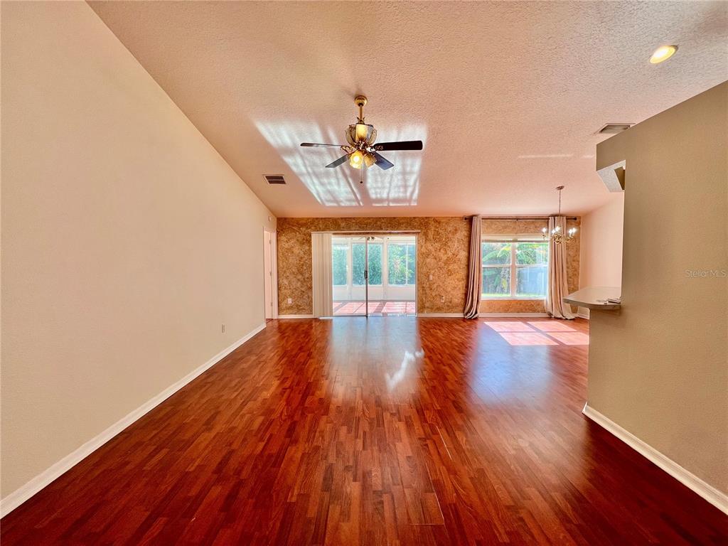 A living room with wood flooring, a ceiling fan, and a sliding door to a patio — 30728 IVERSON DRIVE, WESLEY CHAPEL, FL