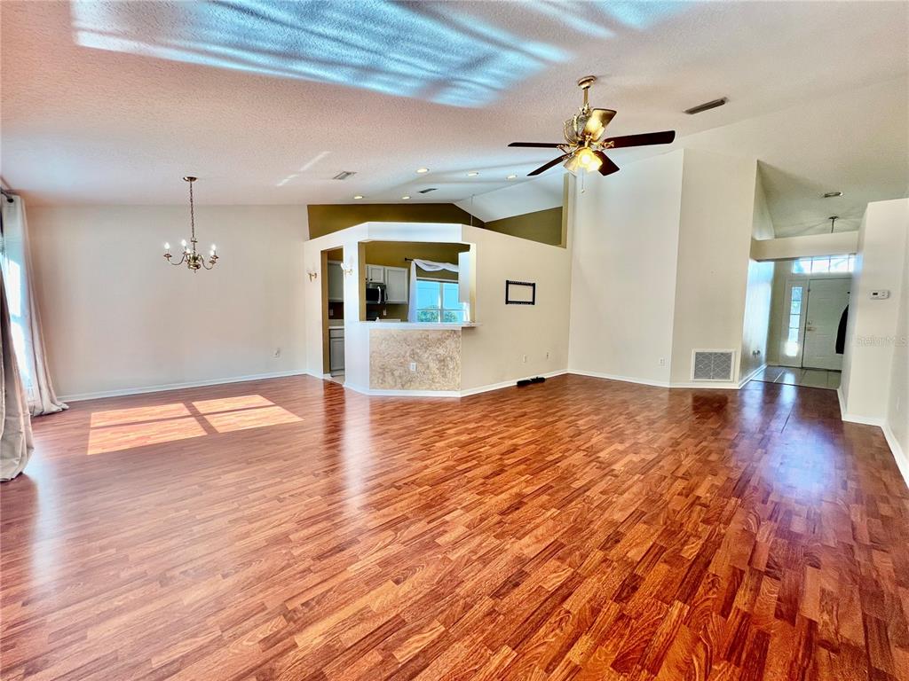 A living area with hardwood floors, a ceiling fan, and an open kitchen pass-through window — 30728 IVERSON DRIVE, WESLEY CHAPEL, FL