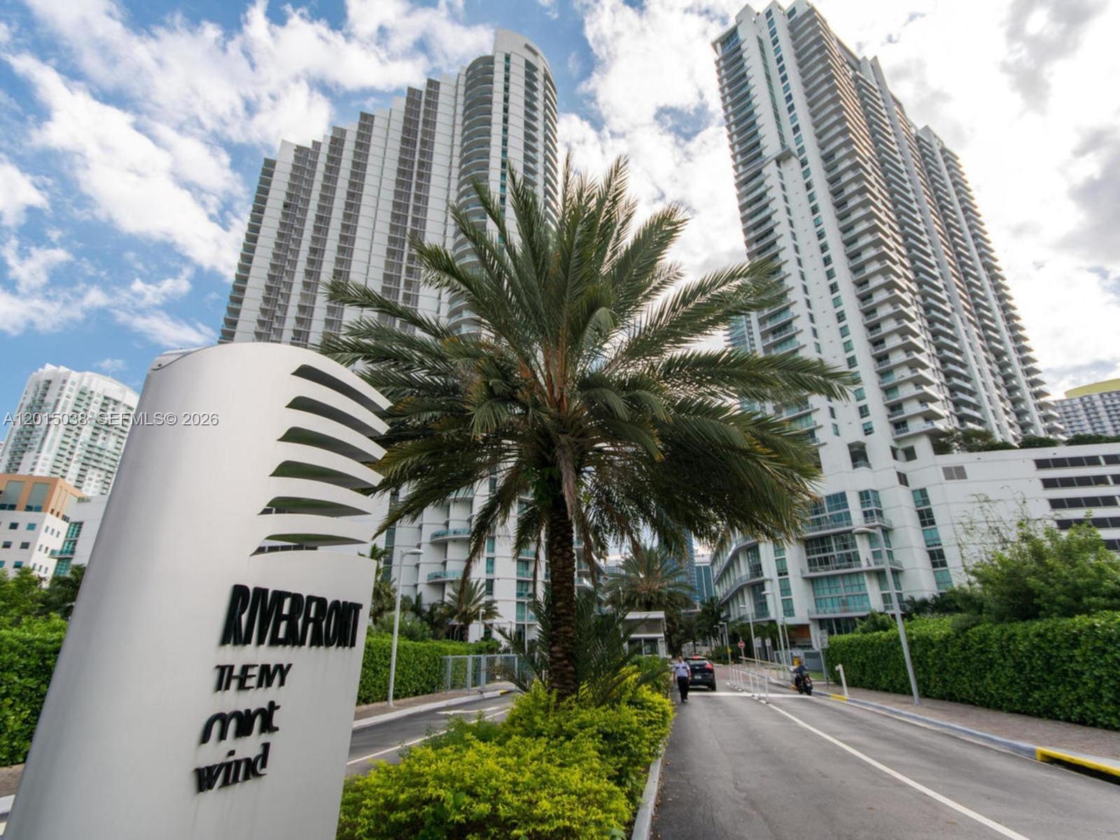 A sign for Riverfront, Mint, and Wind stands before tall residential towers and a palm tree — 350 S Miami Ave # 2713, Miami FL 33130, MIAMI, FL