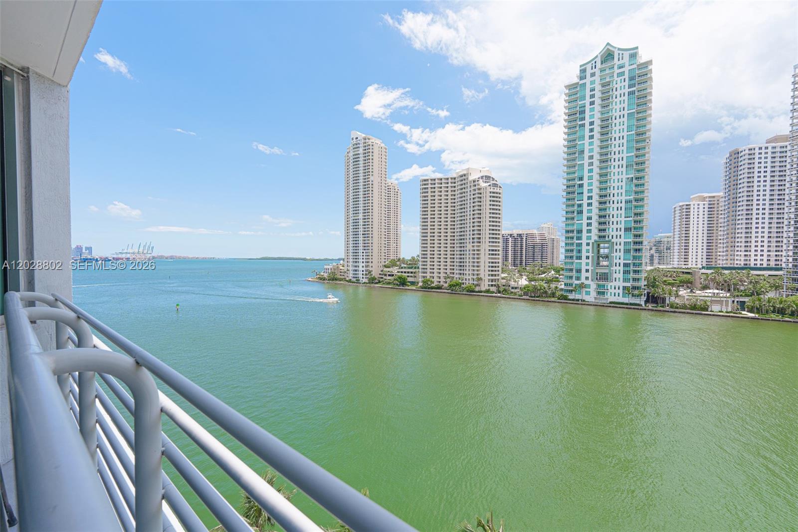 A balcony view overlooks a wide bay with several high-rise apartment buildings in the distance — 325 S Biscayne Blvd # 821, Miami FL 33131, MIAMI, FL