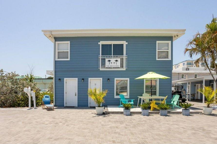 A two-story blue house with a balcony, patio furniture, and a paved driveway — 602 POINSETTIA AVENUE, CLEARWATER BEACH, FL