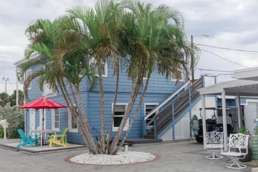 A blue two-story house with an outdoor staircase, palm trees, and patio furniture — 602 POINSETTIA AVENUE, CLEARWATER BEACH, FL