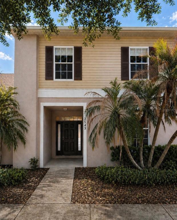 An open-concept living area features beige carpeting, a sliding glass door, and an adjacent kitchen — 2543 OLD KENT CIRCLE, KISSIMMEE, FL