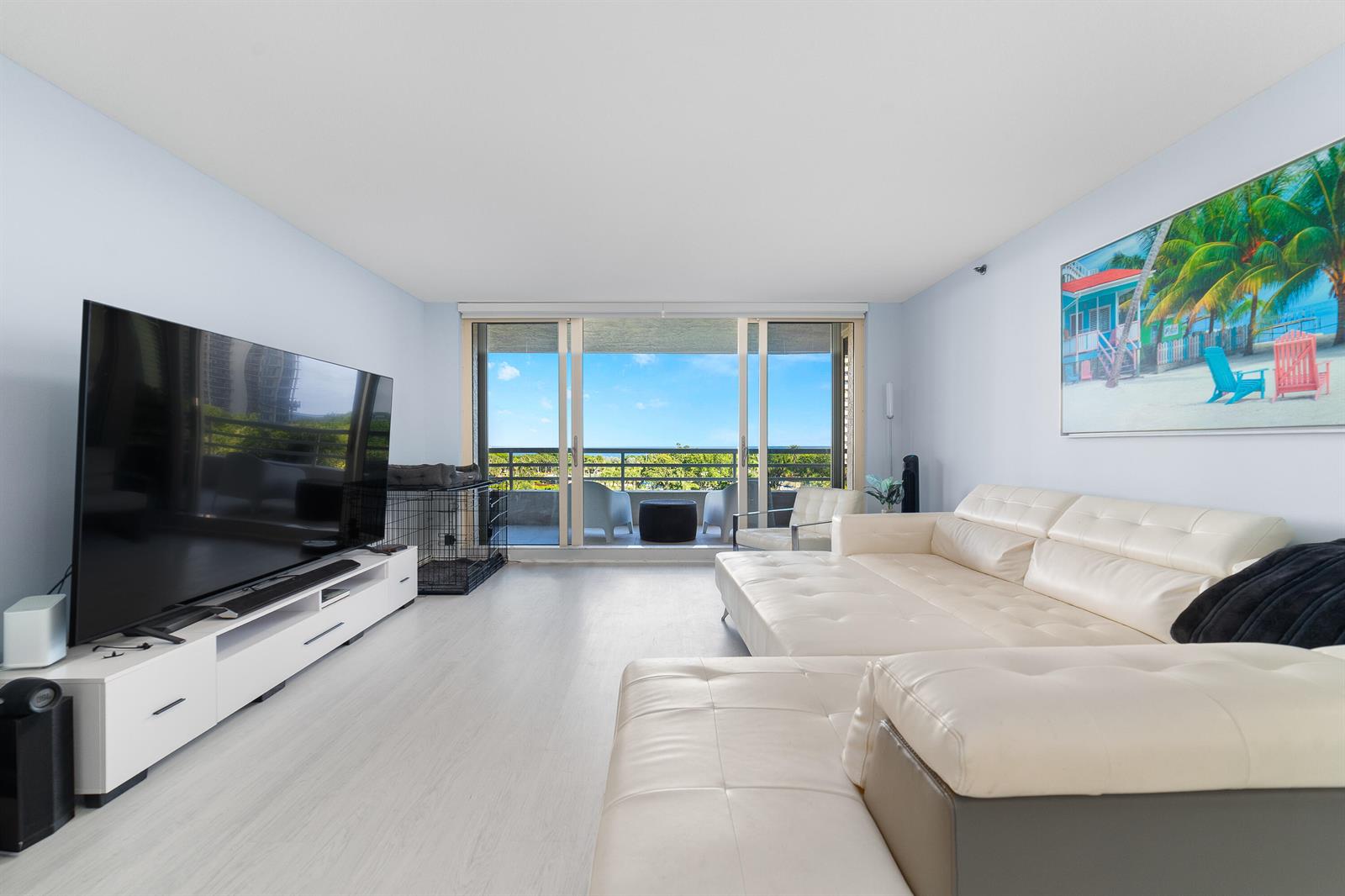 A bright living room features a large white sectional sofa, a television, and a balcony view — 4101 N Ocean Boulevard # 505, Boca Raton FL 33431, BOCA RATON, FL