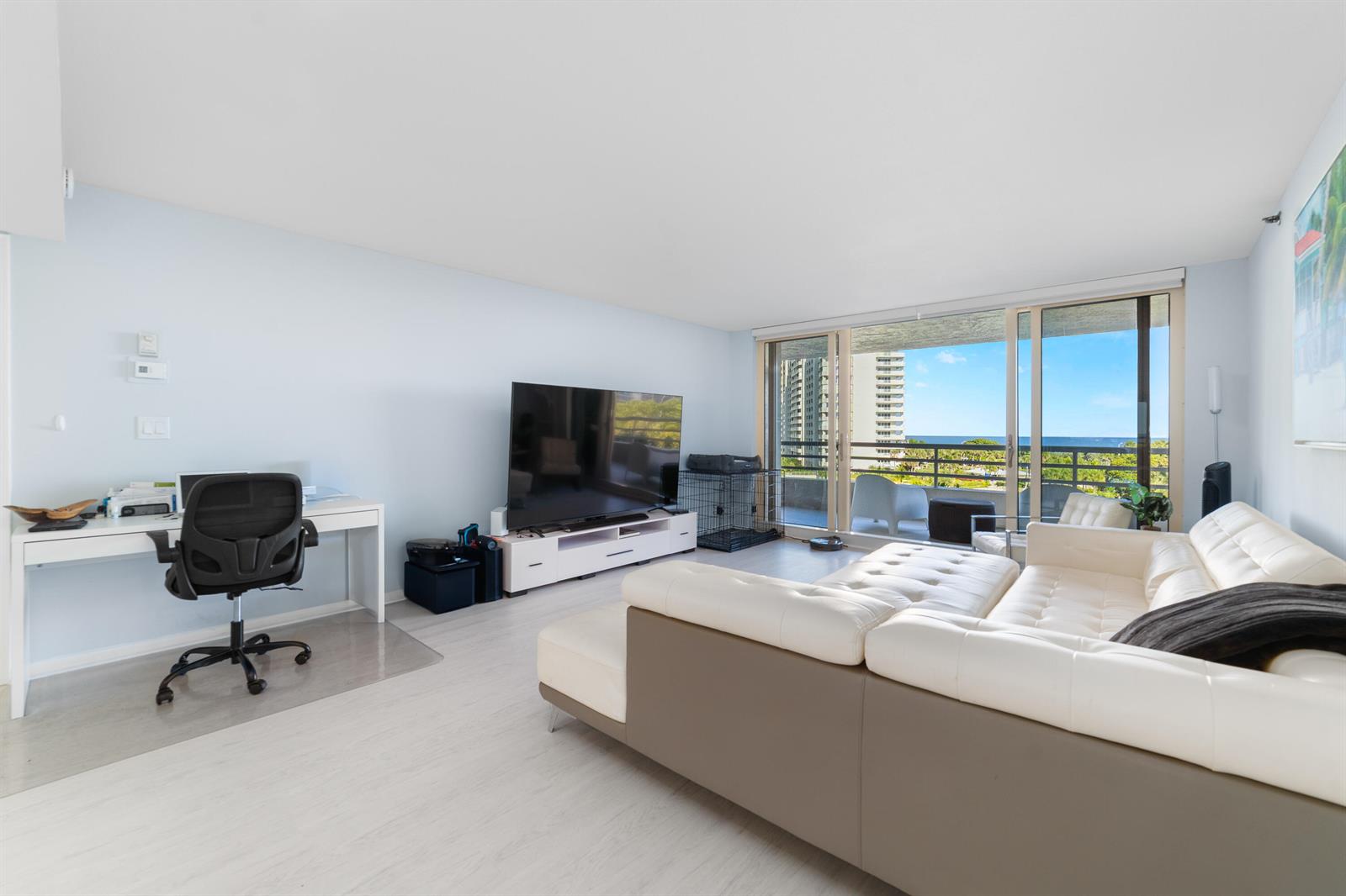 A living room features a white sectional sofa, a television on a stand, and a desk — 4101 N Ocean Boulevard # 505, Boca Raton FL 33431, BOCA RATON, FL