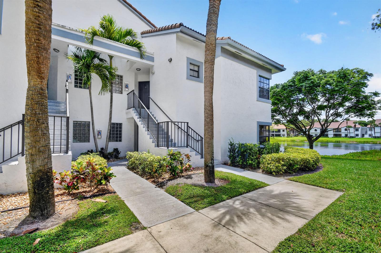 A two-story white stucco apartment building with exterior stairs and a view of a lake — 5394 Firenze Drive, Boynton Beach FL 33437, BOYNTON BEACH, FL