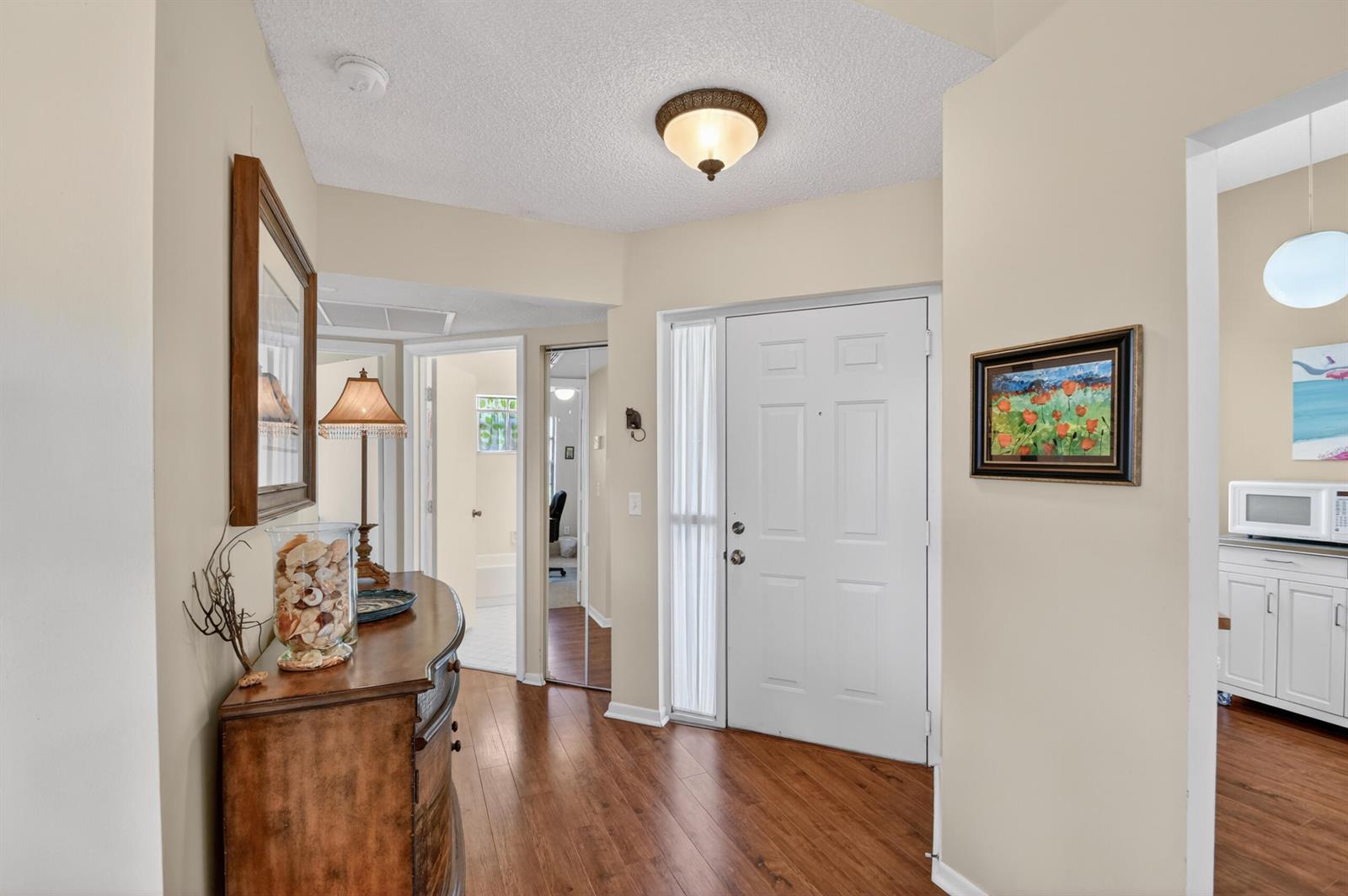 A foyer with wood flooring, a white front door, and a wooden console table — 5394 Firenze Drive, Boynton Beach FL 33437, BOYNTON BEACH, FL