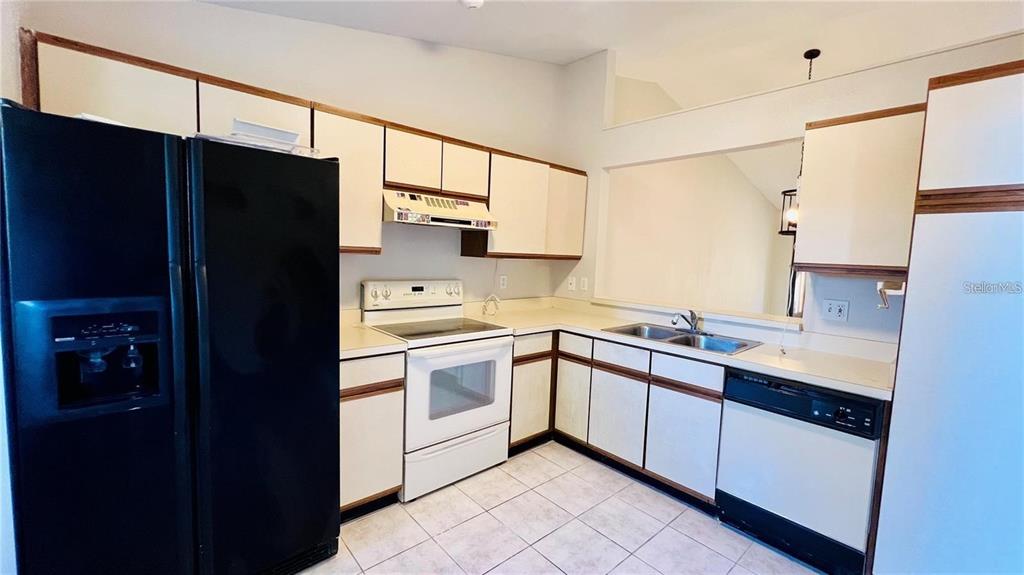 A kitchen features white cabinets, a black refrigerator, a white stove, and a double sink — 2531 KING OAK CIRCLE, ST CLOUD, FL