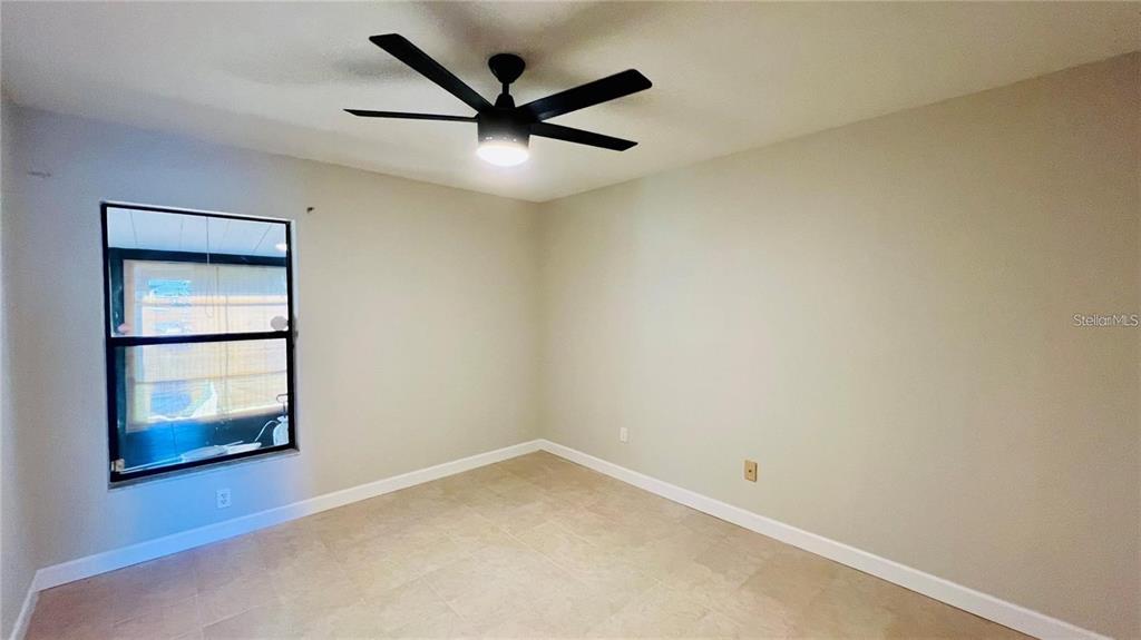 An empty bedroom features light-colored walls, tile flooring, and a ceiling fan — 2531 KING OAK CIRCLE, ST CLOUD, FL