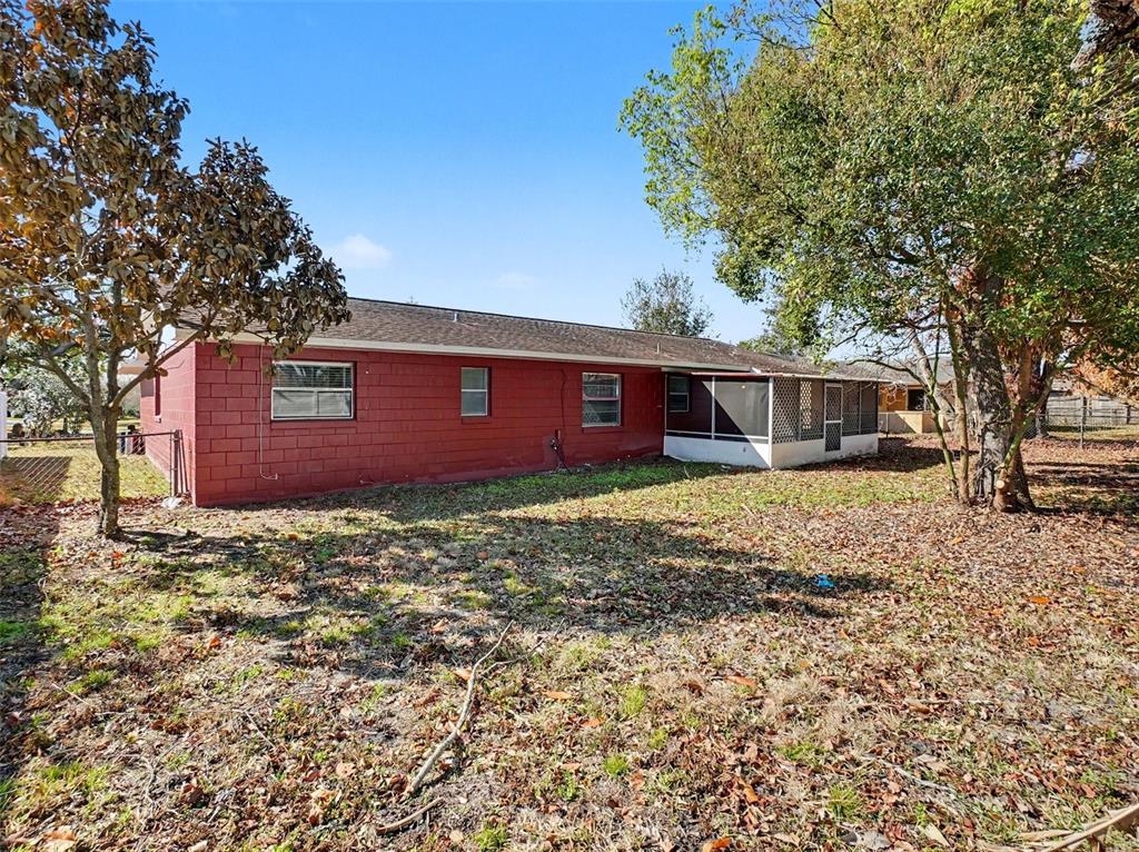 The exterior of a red brick house features a screened-in porch and a large yard — 555 THOMAS JEFFERSON WAY, ORLANDO, FL