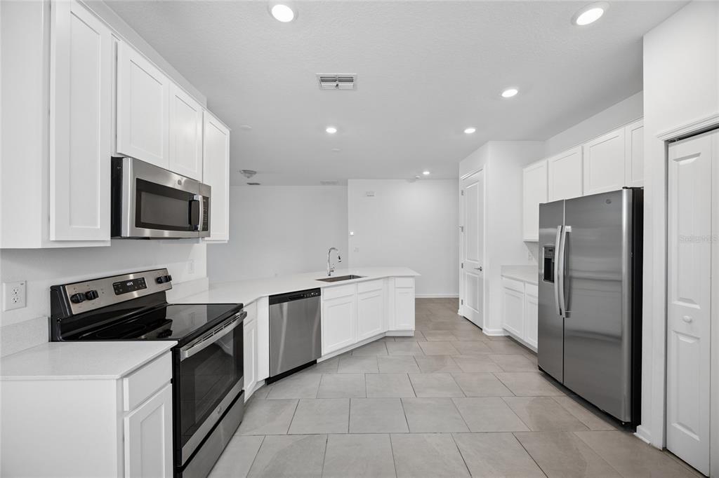 A modern kitchen features white cabinets, stainless steel appliances, and light-colored tile flooring — 363 LOCH COURT, DAVENPORT, FL
