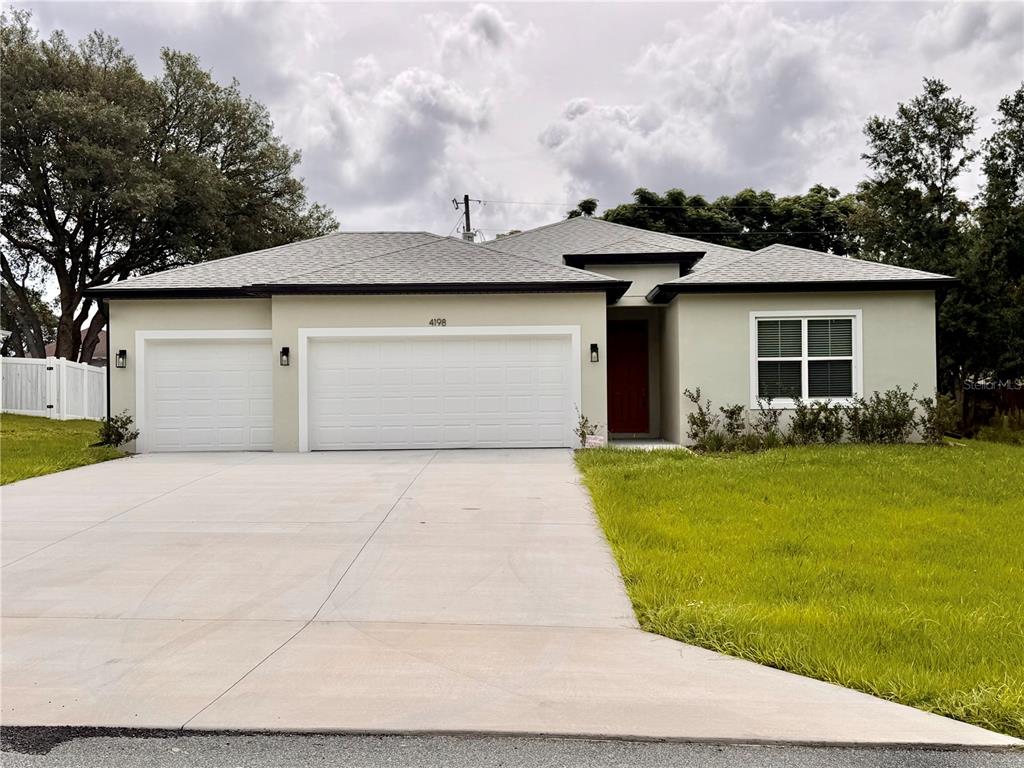 A single-story house with a three-car garage, light-colored stucco exterior, and a concrete driveway — 4198 SW 128TH PLACE, OCALA, FL