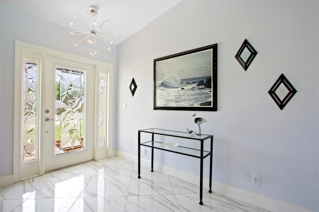 A bright entryway features white marble flooring, a glass console table, and a seascape painting — 1501 NW 7th Street, Boca Raton FL 33486, BOCA RATON, FL