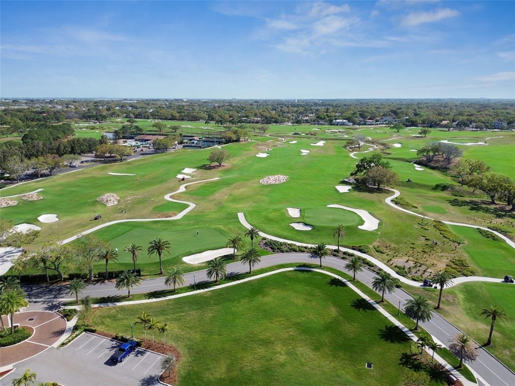 An aerial view of a golf course featuring green fairways, sand bunkers, and palm trees — 100 OAKMONT LANE UNIT 106, BELLEAIR, FL