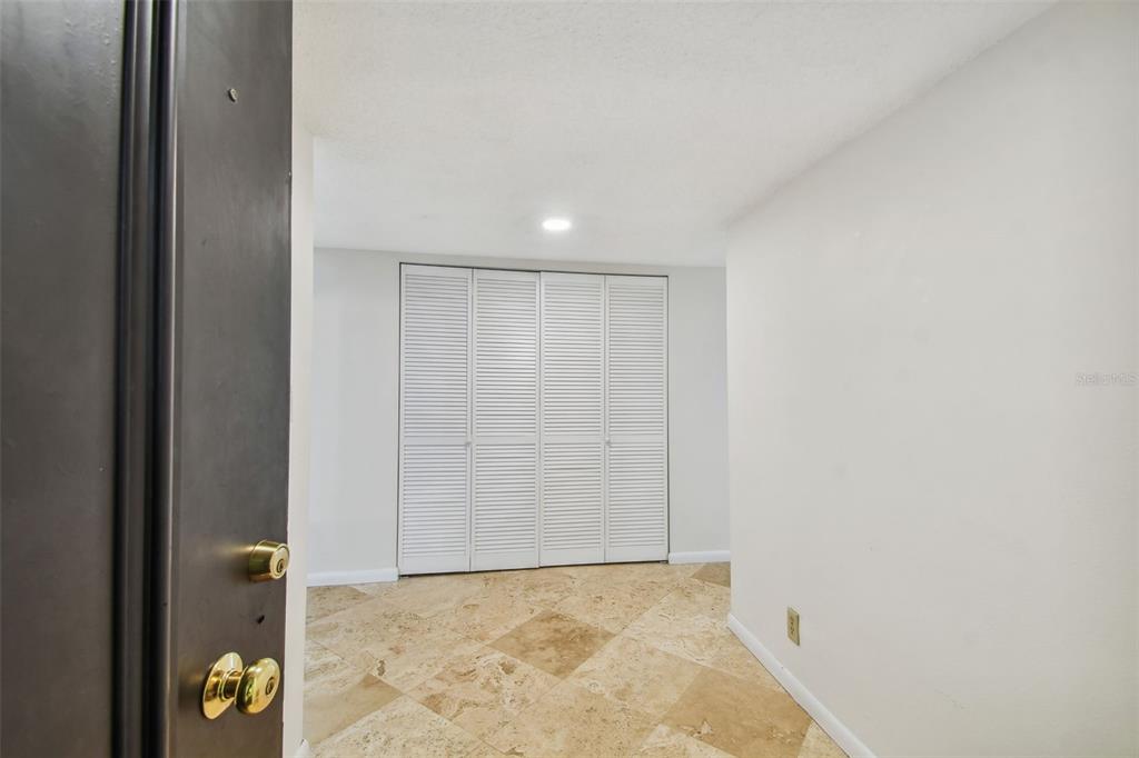 A room with light-colored walls, tiled flooring, and a set of white louvered closet doors — 100 OAKMONT LANE UNIT 106, BELLEAIR, FL