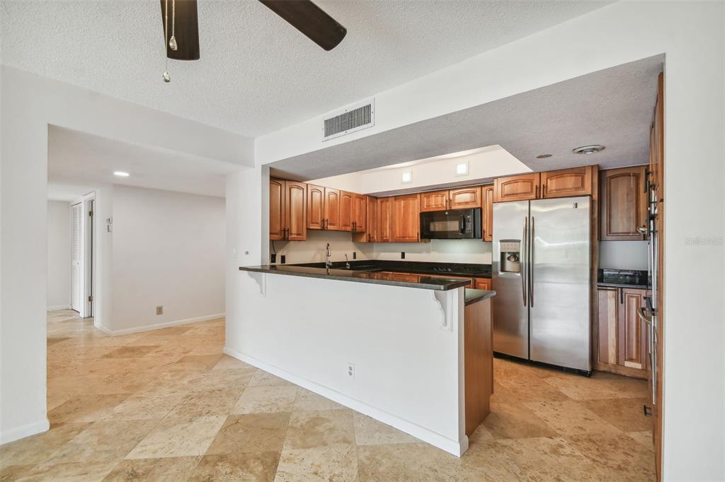 A kitchen with wood cabinets, stainless steel appliances, and a breakfast bar over tile floors — 100 OAKMONT LANE UNIT 106, BELLEAIR, FL