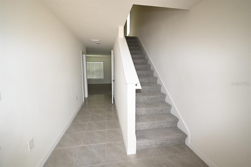A tiled entryway features a carpeted staircase with a white railing leading to an upper floor — 36698 SPANISH ROSE DRIVE, DADE CITY, FL