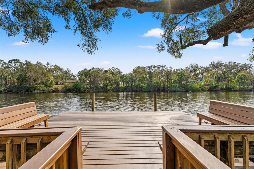 A wooden dock with built-in benches overlooks a river lined with trees — 906 W HENRY AVENUE, TAMPA, FL