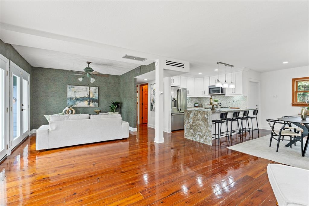An open-concept living and dining area features hardwood floors, a kitchen island, and green walls — 906 W HENRY AVENUE, TAMPA, FL