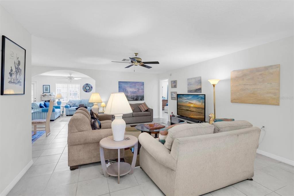 A living room features light tile floors, two beige sofas, and a television on a stand — 9052 ARUNDLE PLACE, NEW PORT RICHEY, FL