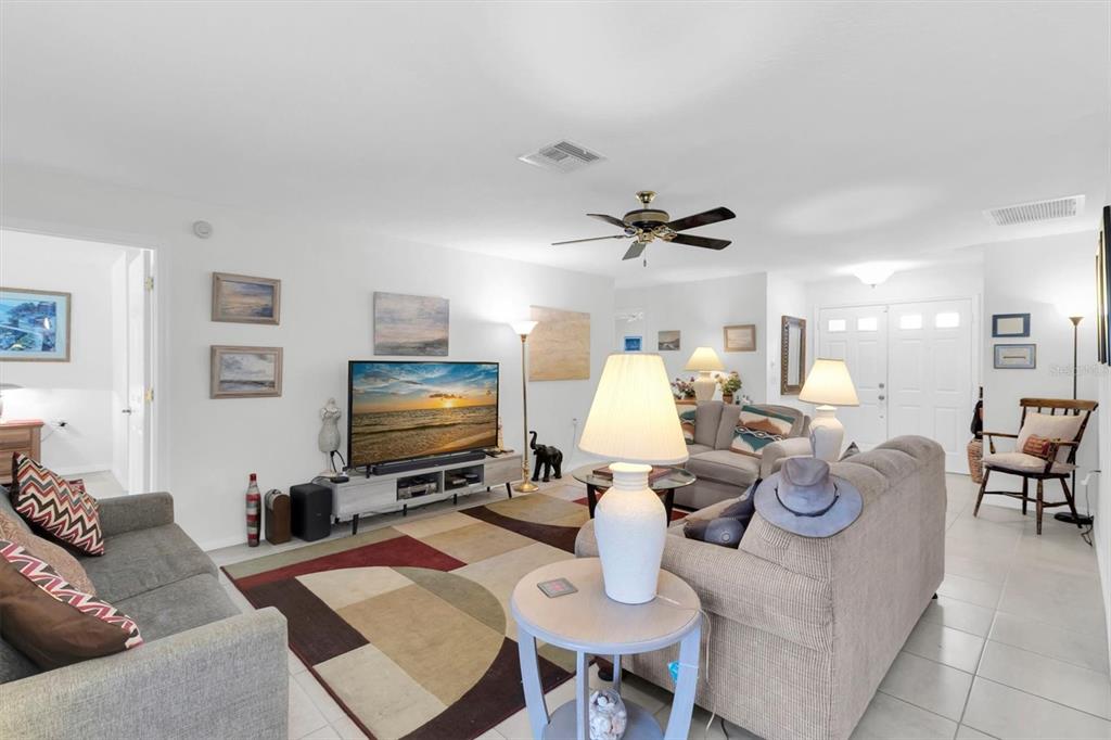 A living room features a television, two sofas, a patterned area rug, and a ceiling fan — 9052 ARUNDLE PLACE, NEW PORT RICHEY, FL