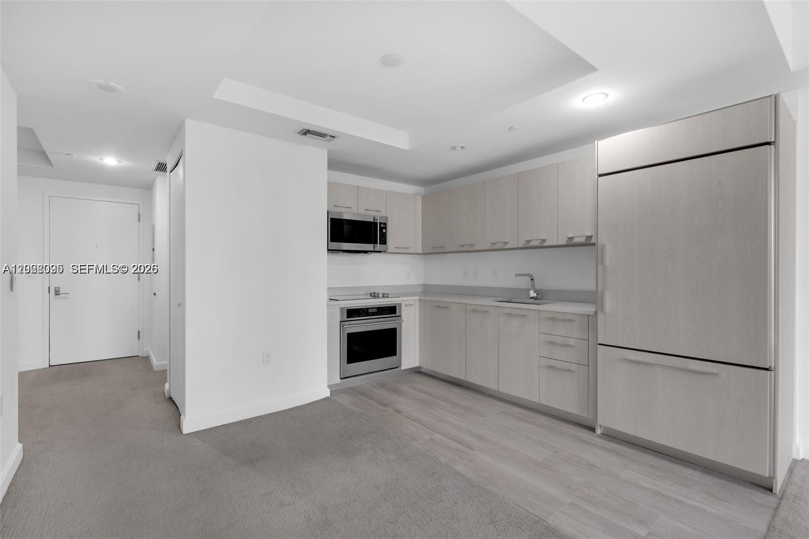 A modern kitchen features light wood cabinetry, stainless steel appliances, and gray flooring — 45 SW 9th St # 2204, Miami FL 33130, MIAMI, FL