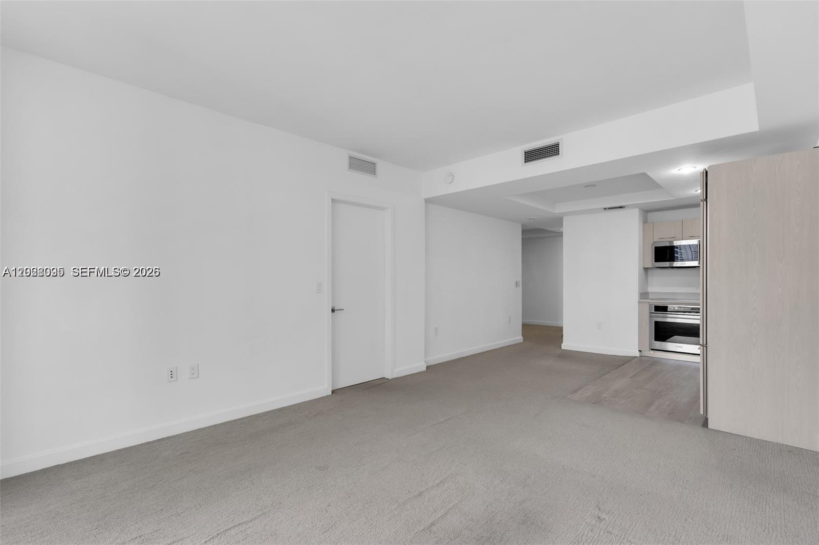 This interior view shows a carpeted living area adjacent to a kitchen with light-colored cabinetry — 45 SW 9th St # 2204, Miami FL 33130, MIAMI, FL